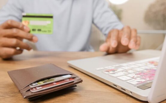 Close-up of hands with a bank card and laptop for online shopping. Perfect for illustrating e-commerce concepts.