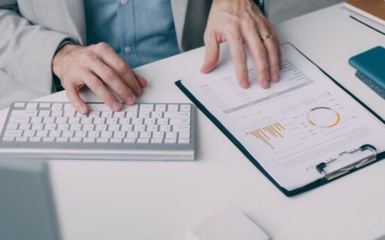 A man working with a financial report and keyboard in an office setting.